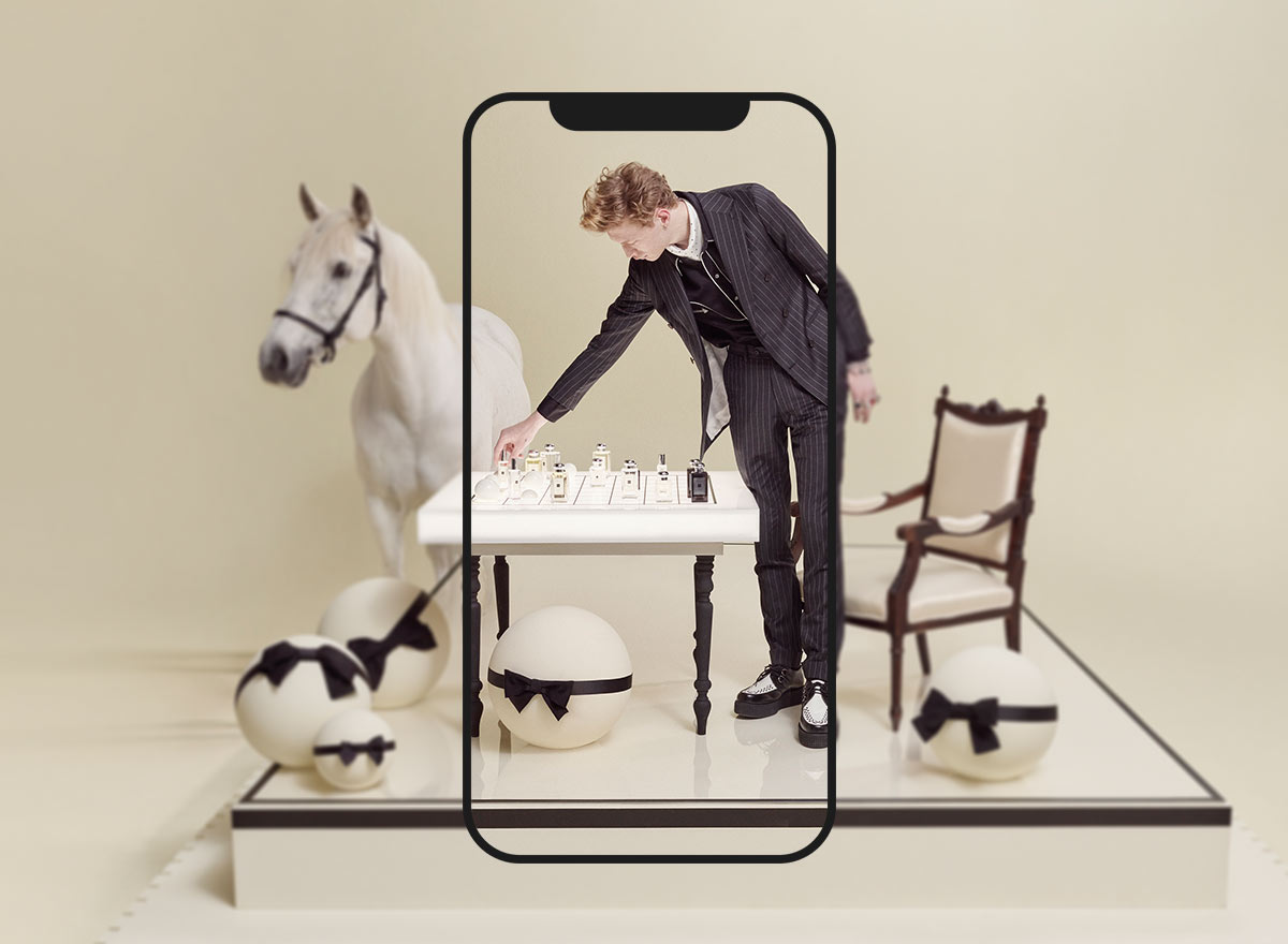 Man playing chess with Jo Malone London colognes on a table